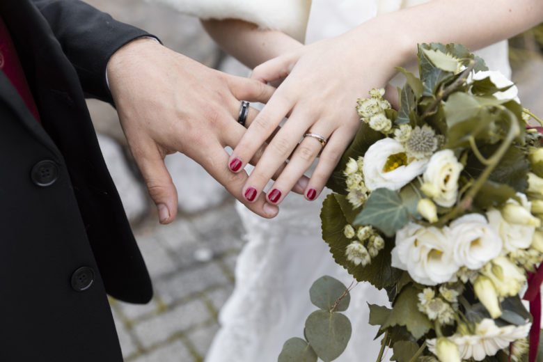 mains des mariés avec les alliances et un joli bouquet de fleurs
