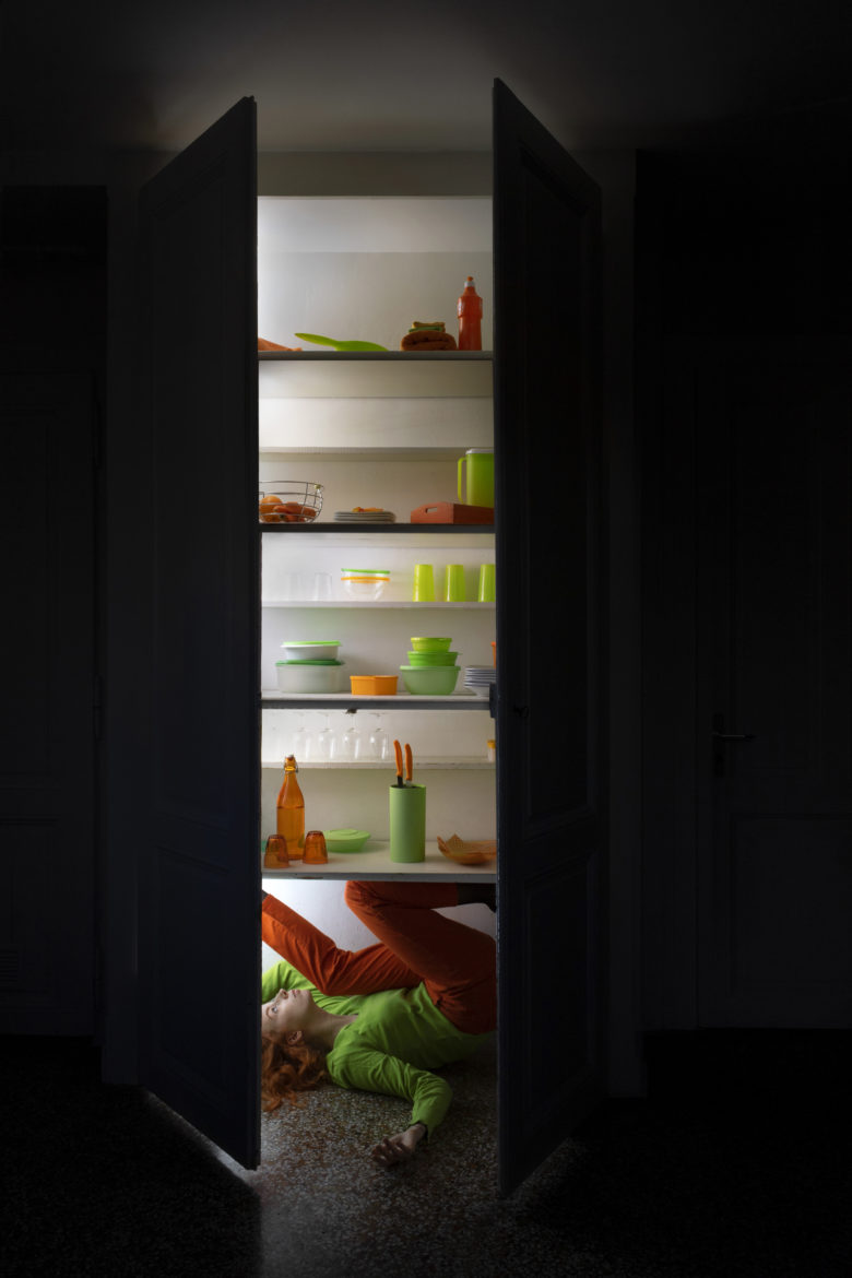 portraits femme dans une armoire de cuisine avec des objets vert et orange