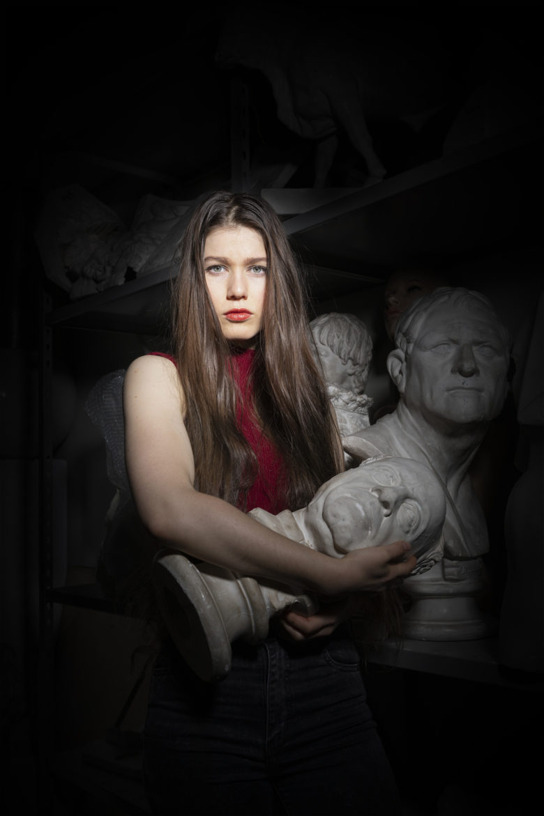 portraits femme dans la nuit avec des statues d art autour d elle