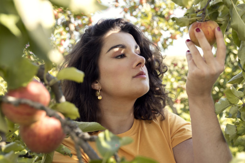 portraits femme dans un verger qui mange une pomme