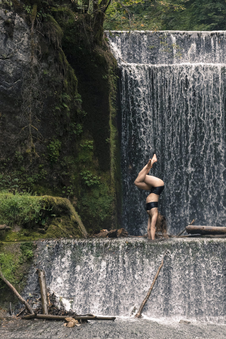 portraits femme faisant le poirier devant une cascade au lac vert